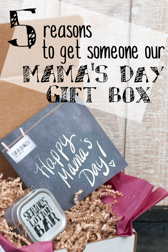 white cardboard box on a black surface with white wood background filled with crinkle paper and all natural lip care and skin care products and the test "5 reasons to get someone our Mama's Day gift box"